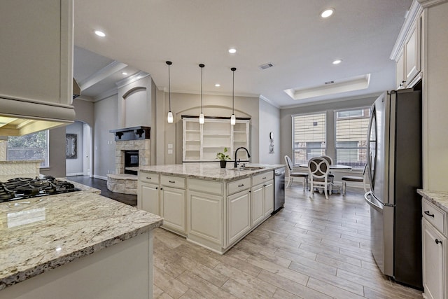 kitchen featuring light stone countertops, a fireplace, stainless steel appliances, and a center island with sink