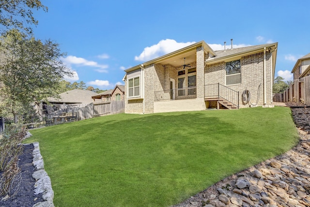 back of property featuring ceiling fan and a lawn