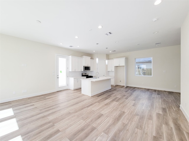 kitchen featuring light hardwood / wood-style floors, white cabinetry, a kitchen island with sink, and stainless steel appliances