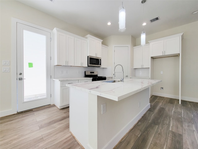 kitchen with a kitchen island with sink, pendant lighting, white cabinets, and stainless steel appliances