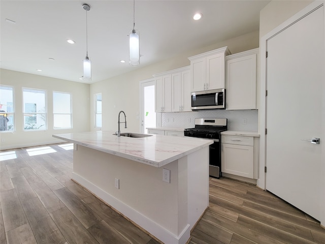 kitchen with sink, white cabinets, stainless steel appliances, and an island with sink