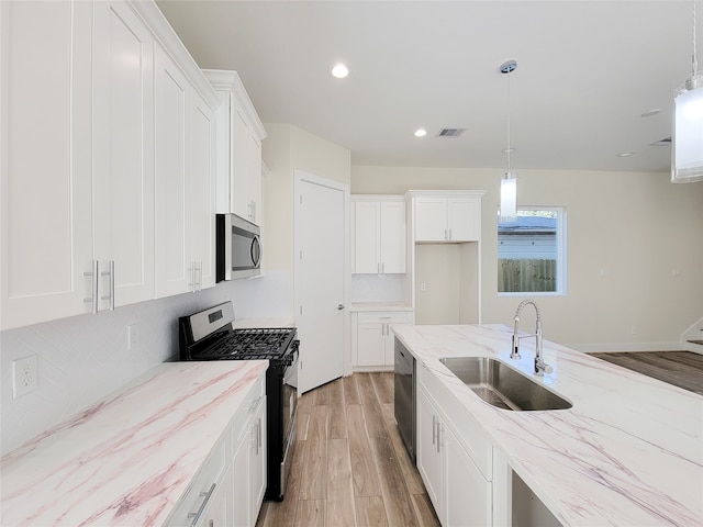 kitchen featuring appliances with stainless steel finishes, white cabinetry, sink, and hanging light fixtures