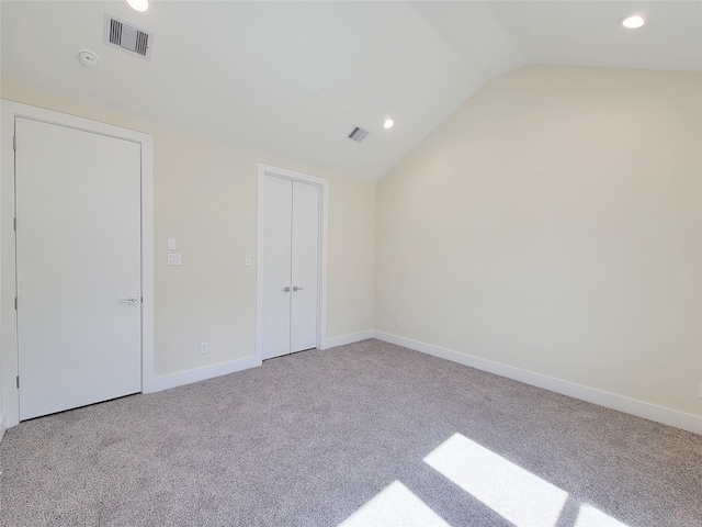 carpeted spare room featuring vaulted ceiling