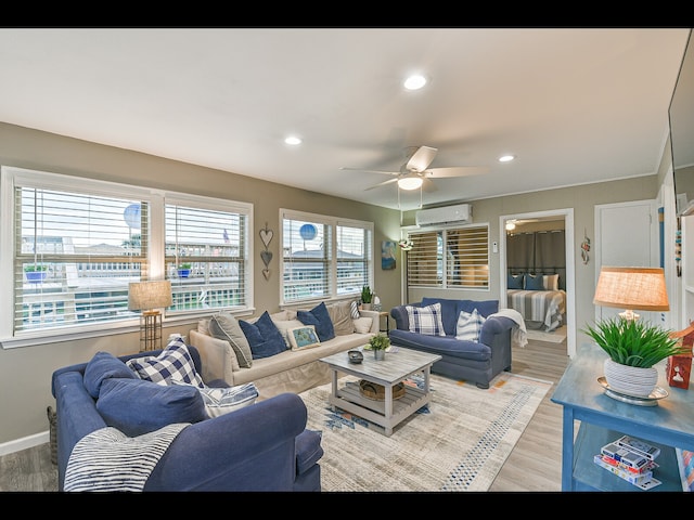 living room with light wood-type flooring, ceiling fan, and a wall mounted air conditioner