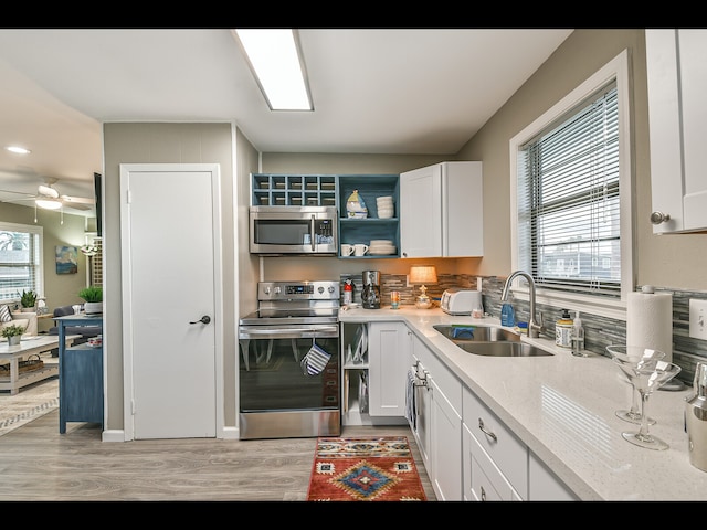 kitchen featuring white cabinetry, appliances with stainless steel finishes, light wood-type flooring, a wealth of natural light, and sink