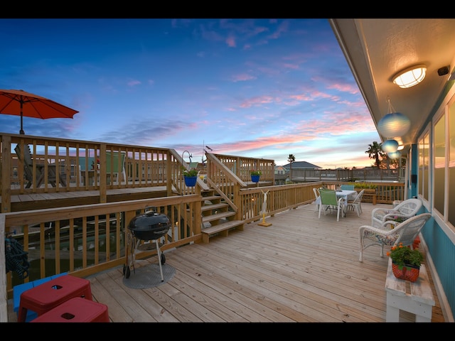 deck at dusk featuring a grill