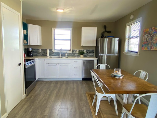 kitchen featuring stainless steel appliances, a healthy amount of sunlight, tasteful backsplash, white cabinets, and sink