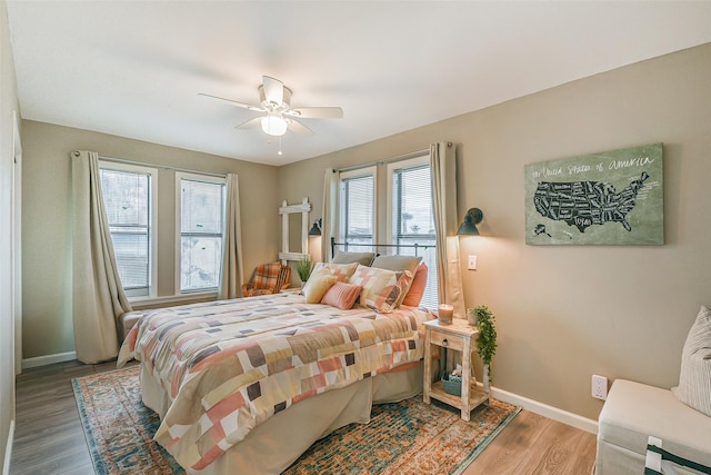 bedroom featuring ceiling fan, wood-type flooring, and multiple windows