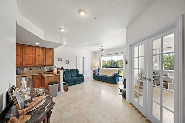 tiled living room with french doors, a textured ceiling, sink, and ceiling fan