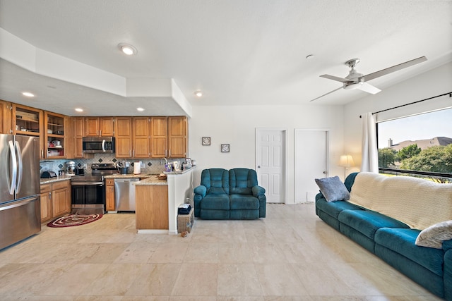 interior space featuring tasteful backsplash, stainless steel appliances, light stone countertops, and ceiling fan