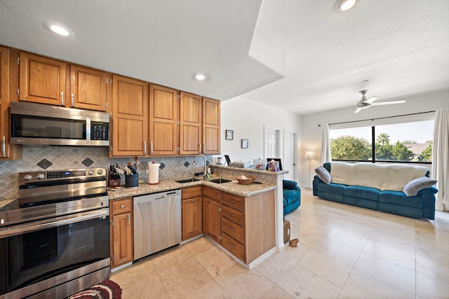 kitchen with appliances with stainless steel finishes, kitchen peninsula, tasteful backsplash, and sink