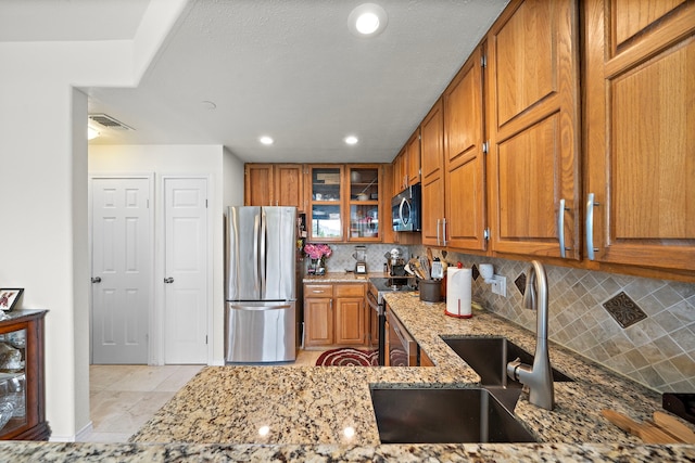 kitchen featuring light stone countertops, stainless steel appliances, tasteful backsplash, and sink