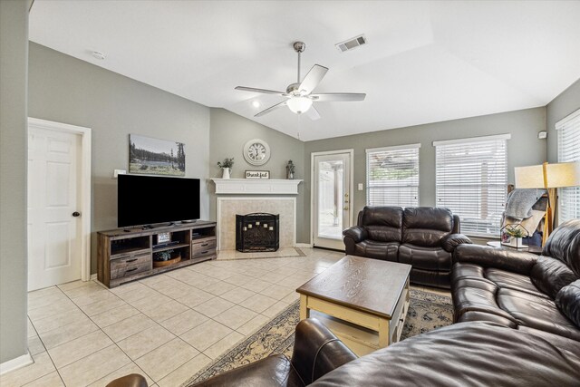 living room with a tiled fireplace, ceiling fan, lofted ceiling, and light tile patterned floors