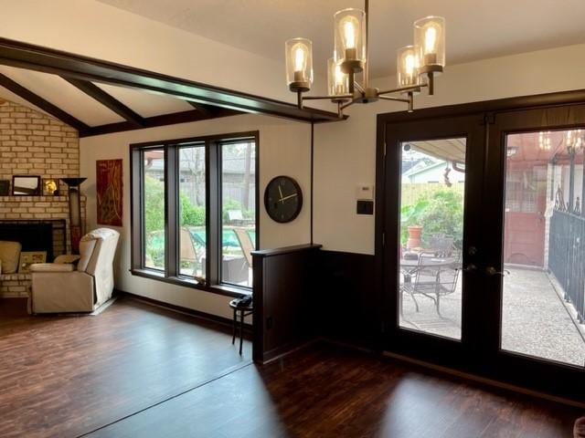 doorway featuring a fireplace, vaulted ceiling, a wealth of natural light, and french doors