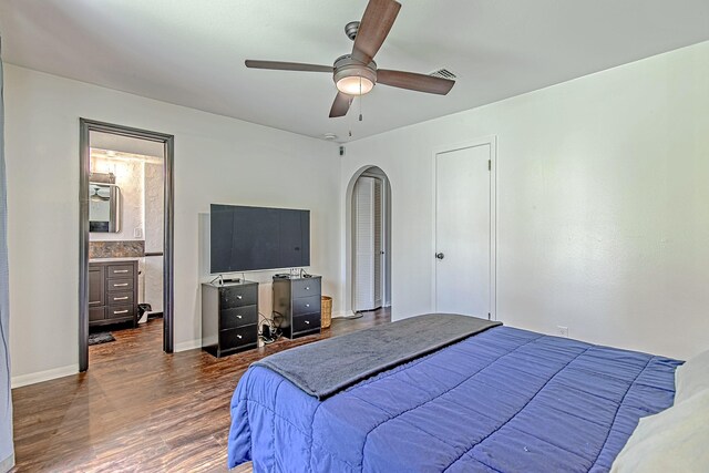 bedroom with arched walkways, ceiling fan, visible vents, baseboards, and dark wood-style floors