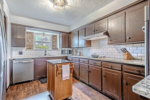 kitchen featuring under cabinet range hood, dark wood-style floors, stainless steel appliances, and a sink