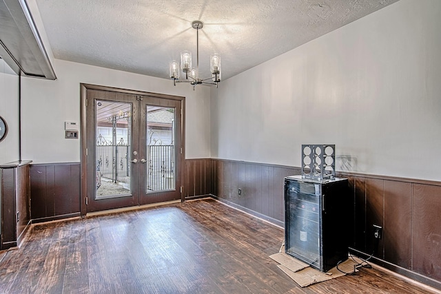 entryway with a textured ceiling, french doors, wood finished floors, and wainscoting