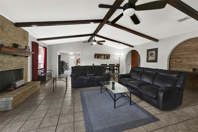 tiled living room featuring ceiling fan, a fireplace, and lofted ceiling with beams