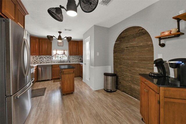 kitchen with sink, light hardwood / wood-style flooring, decorative backsplash, a kitchen island, and stainless steel appliances