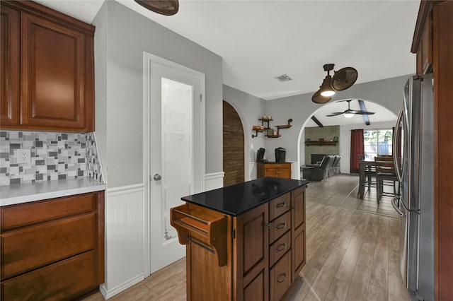 kitchen with decorative backsplash, stainless steel fridge, ceiling fan, and light wood-type flooring