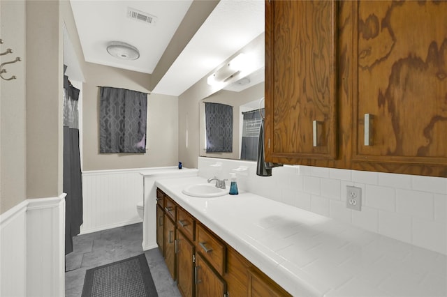 bathroom with vanity, toilet, and tasteful backsplash