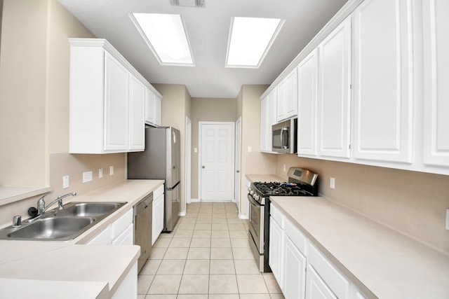 kitchen with sink, appliances with stainless steel finishes, white cabinetry, and light tile patterned flooring