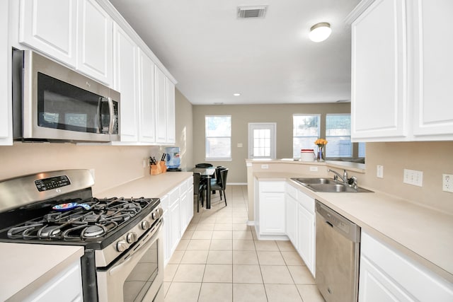 kitchen with light tile patterned flooring, appliances with stainless steel finishes, sink, and white cabinets