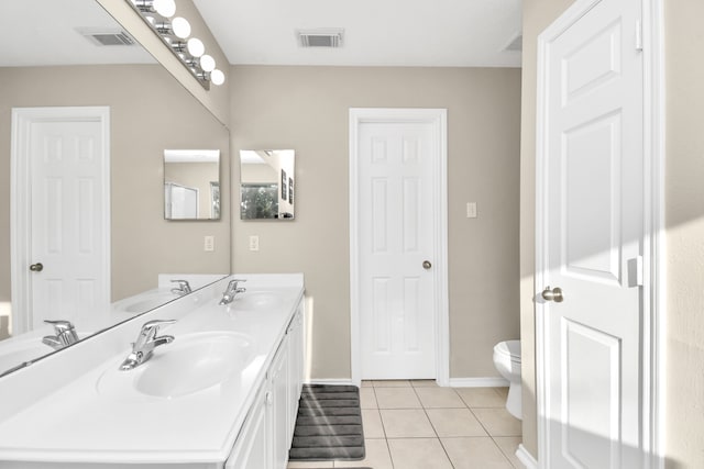 bathroom with toilet, vanity, and tile patterned flooring