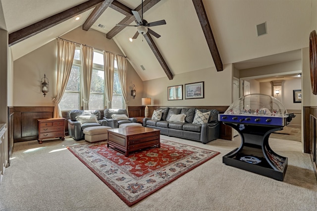 living room featuring light carpet, beamed ceiling, wooden walls, and ceiling fan