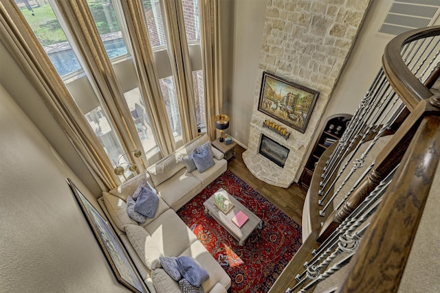 living room with a fireplace, hardwood / wood-style flooring, and a towering ceiling