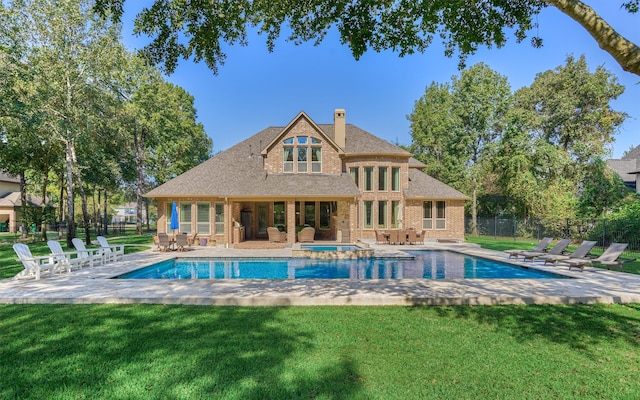 back of house with a lawn, a patio area, and a pool with hot tub