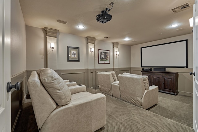 home theater featuring light carpet, a textured ceiling, and ornate columns