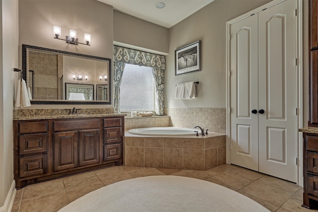 bathroom featuring vanity, tiled bath, and tile patterned flooring