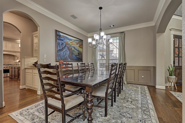 dining area featuring an inviting chandelier, crown molding, and dark wood-type flooring