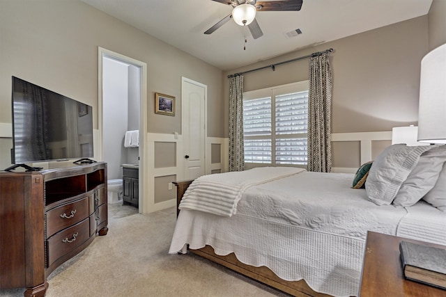 bedroom featuring ensuite bath, light colored carpet, and ceiling fan