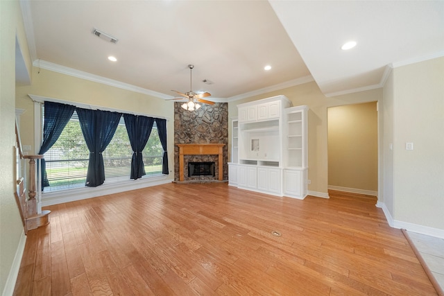 unfurnished living room featuring a stone fireplace, crown molding, light wood-type flooring, and ceiling fan