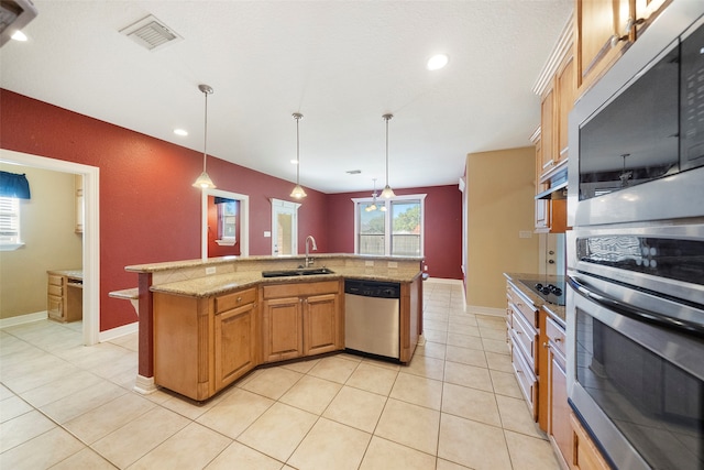 kitchen featuring sink, appliances with stainless steel finishes, decorative light fixtures, and a kitchen island with sink