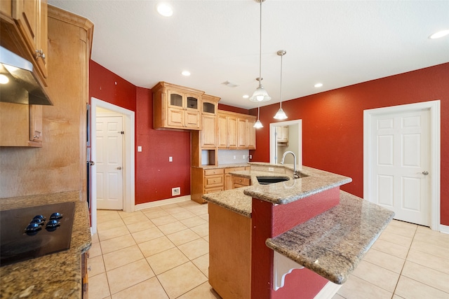 kitchen featuring hanging light fixtures, a center island with sink, light tile patterned floors, sink, and black stovetop