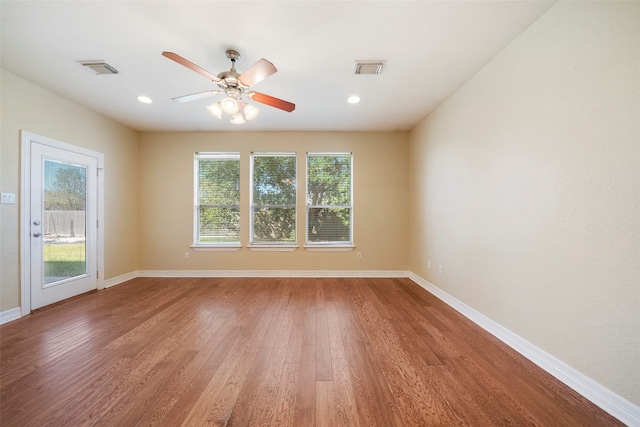 empty room featuring ceiling fan, a healthy amount of sunlight, and hardwood / wood-style floors