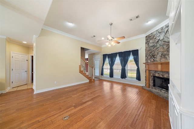 unfurnished living room with ceiling fan, a stone fireplace, ornamental molding, and light hardwood / wood-style flooring