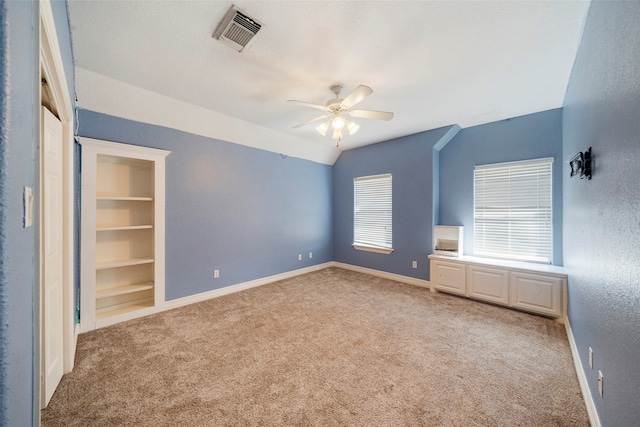 interior space with lofted ceiling, carpet, built in shelves, and ceiling fan