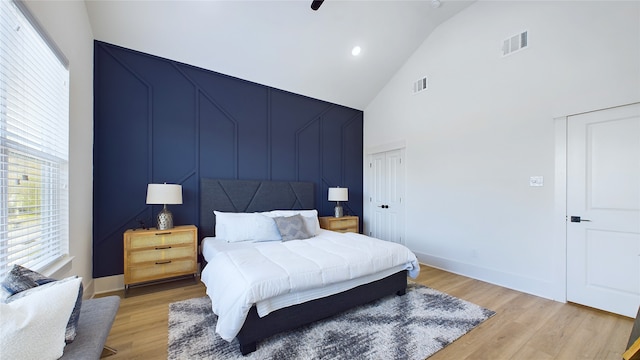 bedroom with high vaulted ceiling, ceiling fan, and light hardwood / wood-style flooring