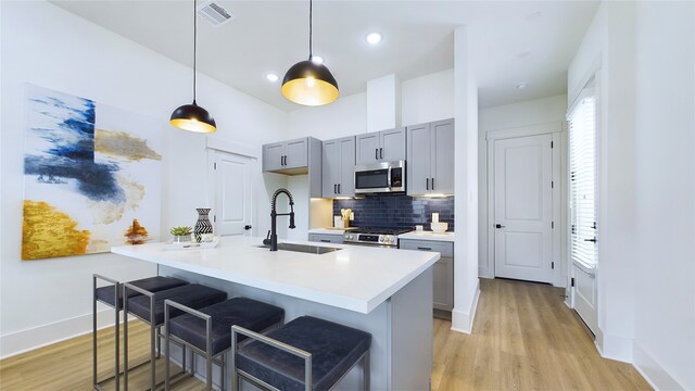 kitchen featuring appliances with stainless steel finishes, sink, a breakfast bar area, decorative backsplash, and hanging light fixtures