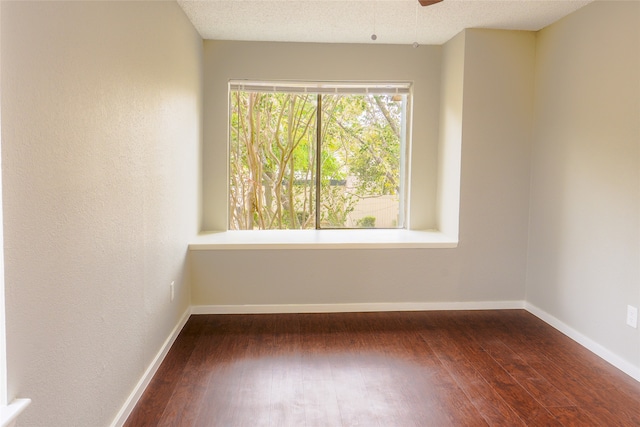 empty room with a textured ceiling and dark hardwood / wood-style flooring