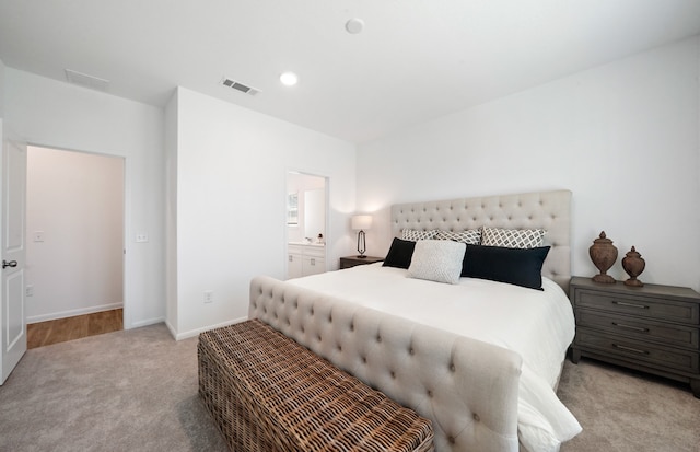 bedroom with light carpet and ensuite bathroom