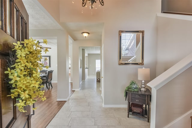 entrance foyer with light tile patterned floors, a textured ceiling, and a notable chandelier