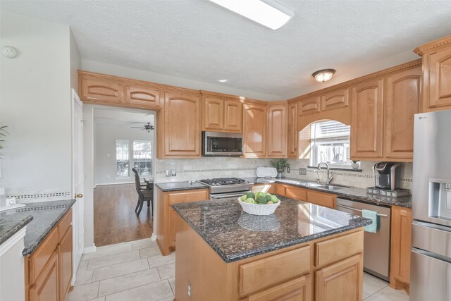 kitchen featuring appliances with stainless steel finishes, ceiling fan, sink, light tile patterned floors, and a kitchen island