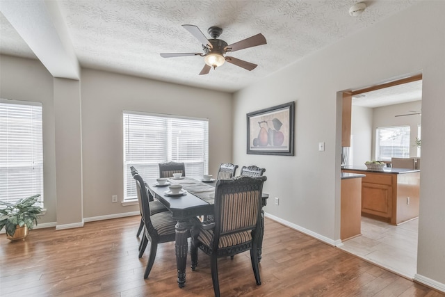 dining area with a textured ceiling, light hardwood / wood-style floors, a wealth of natural light, and ceiling fan