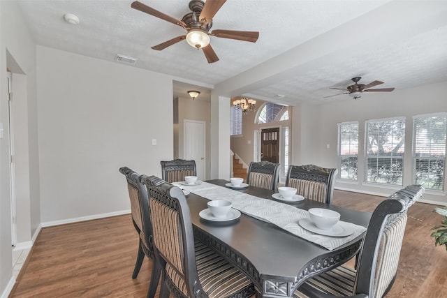 dining room featuring ceiling fan with notable chandelier, hardwood / wood-style floors, and a textured ceiling