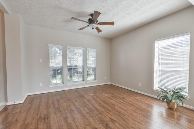 unfurnished room with wood-type flooring, a textured ceiling, plenty of natural light, and ceiling fan